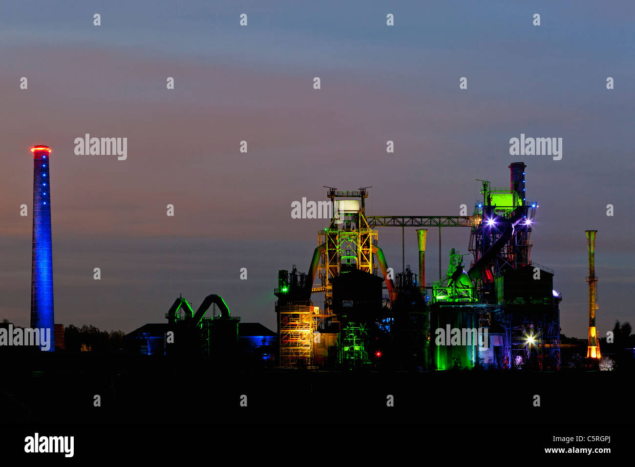 Germany Illuminated blast furnace and smoke stacks of old industrial plant Stock Photo