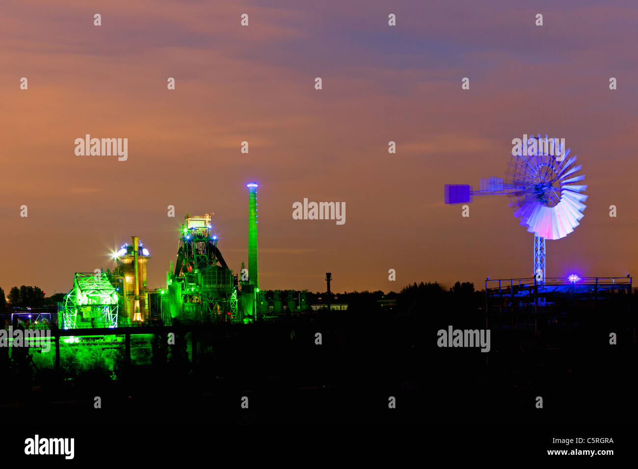 Germany Illuminated blast furnace and wind mill of industrial plant at night Stock Photo