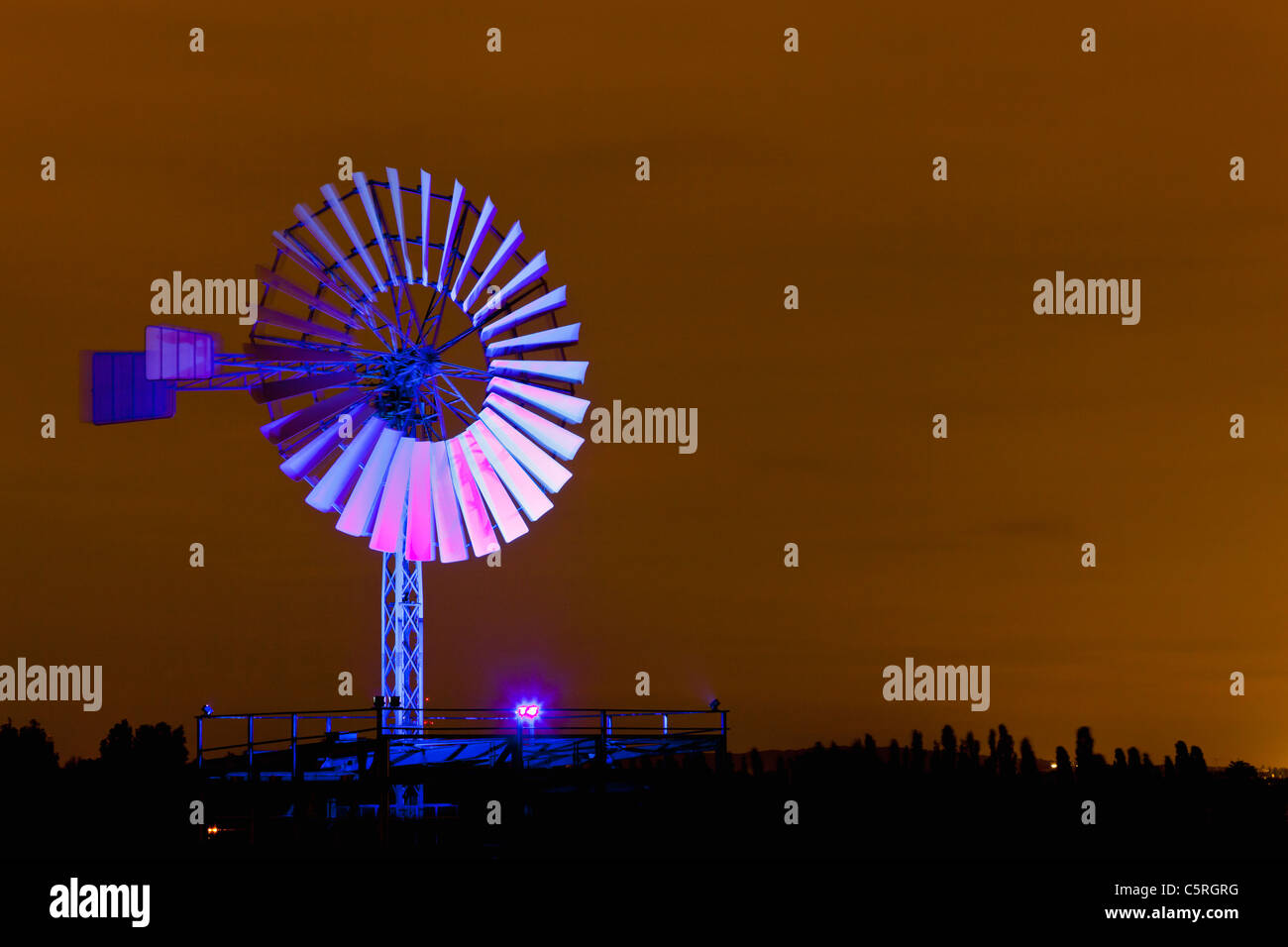 Germany, Nordrhein-Westfalen, Duisburg, Duisburg-Nord Landscape Park, View of illuminated wind mill of industrial plant at night Stock Photo