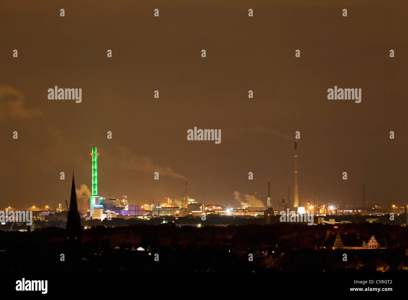 Germany, Nordrhein-Westfalen, Duisburg, View of illuminated green tower and industrial plant at night Stock Photo