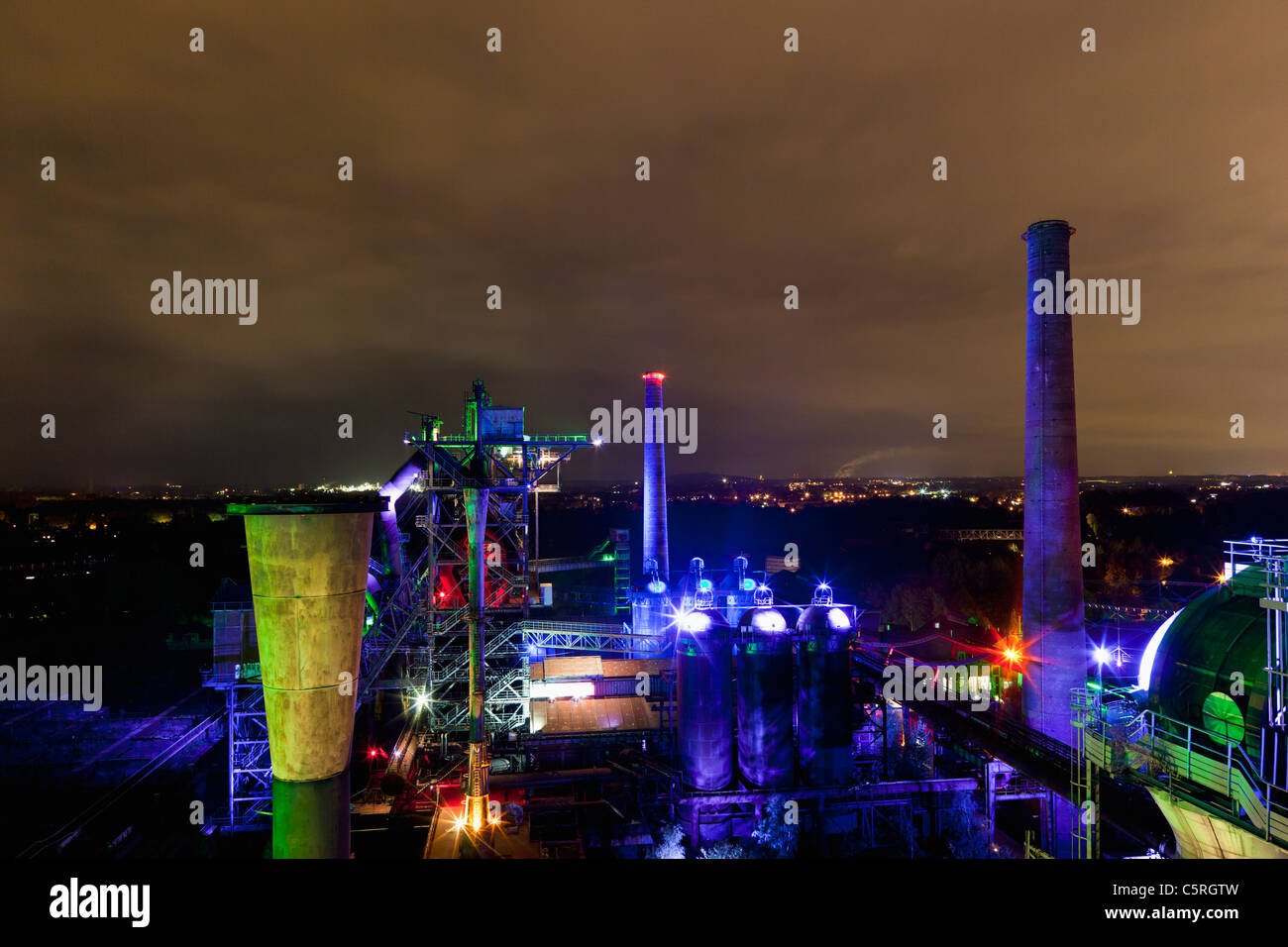 Germany  Illuminated blast furnace and smoke stacks of old industrial plant Stock Photo
