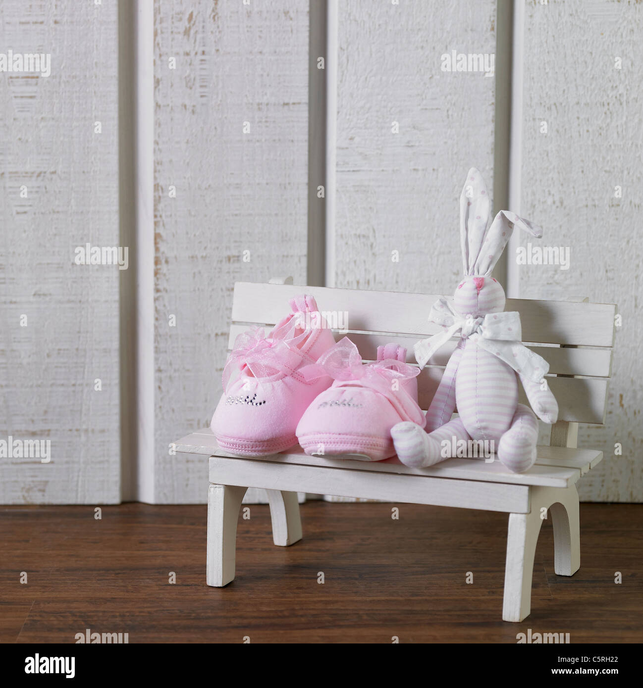 Baby's shoes and a doll on a bench figurine Stock Photo