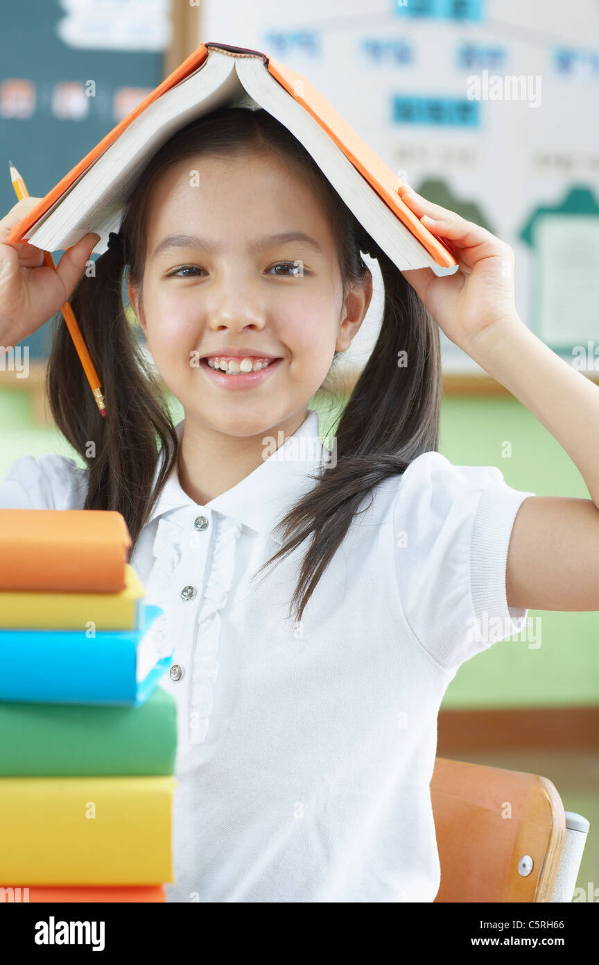 An asian girl putting a book on her head Stock Photo - Alamy