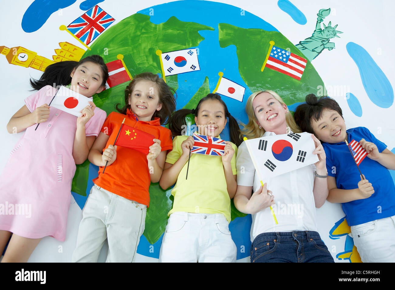 Students and a teacher lying down holding flags Stock Photo