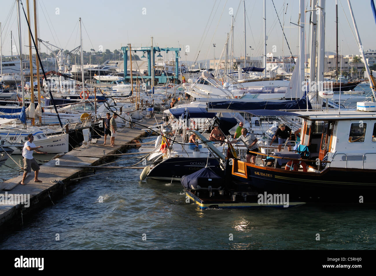 Eivissa, Ibiza, Spain, yachtsmen prepare to tie up in a marina as a rope is thrown Stock Photo