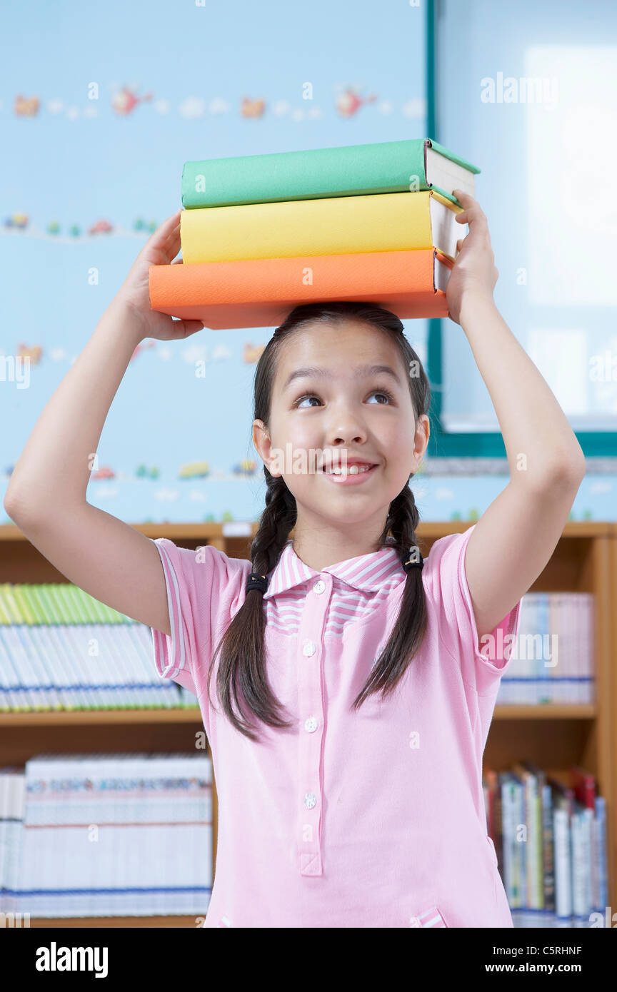 An Asian girl holding up books on her head Stock Photo - Alamy