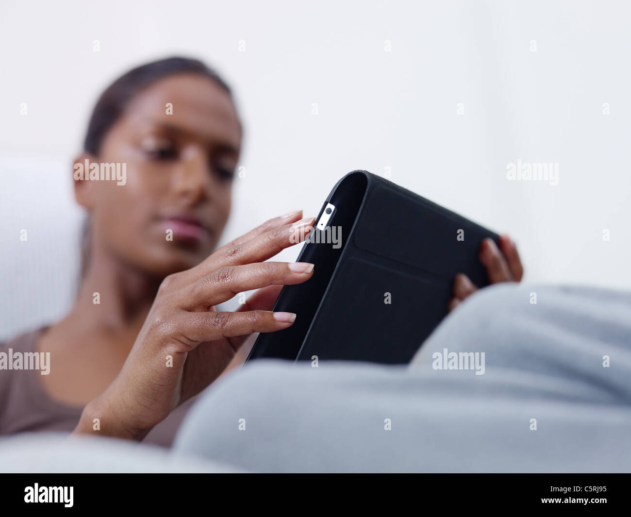 close up of mid adult indian woman relaxing on sofa and using touch pad computer. selective focus, copy space Stock Photo