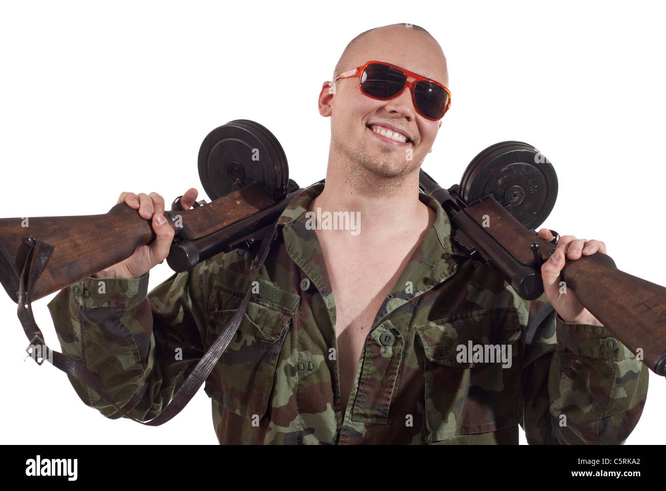 Smiling soldier with sunglasses and two machine guns. Stock Photo