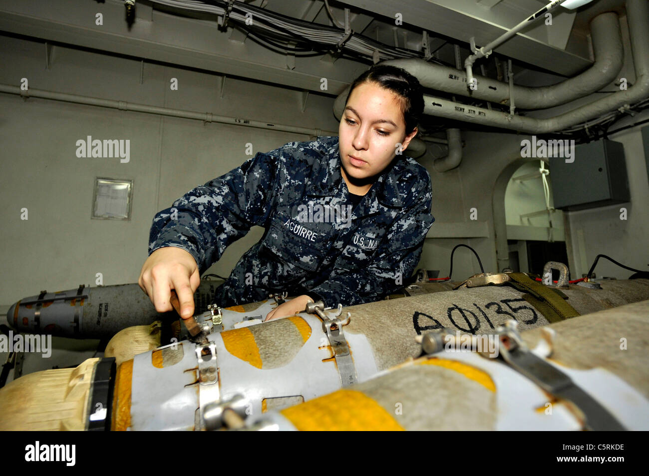 Aviation Ordnanceman Airman Katelyn Aguirre, from Monahans, Texas, performs corrosion treatment on a laser-guided bomb Stock Photo