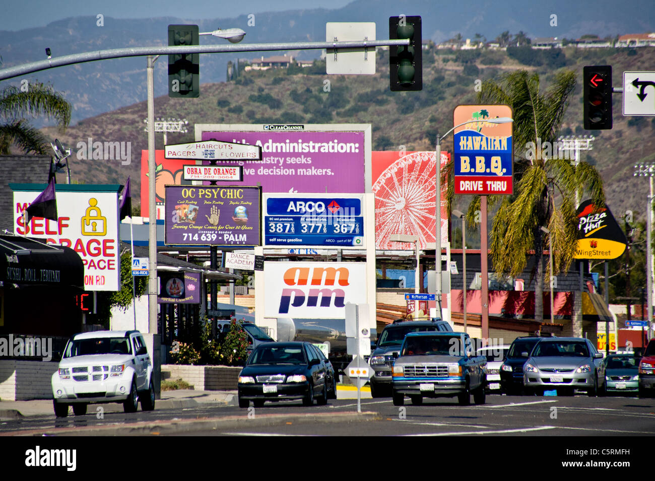 Afternoon traffic passes retail advertising signs in Orange, CA. Stock Photo