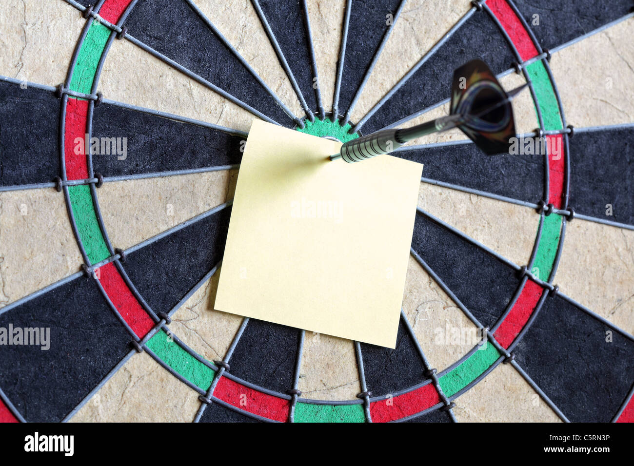 Yellow sticky note on dartboard Stock Photo