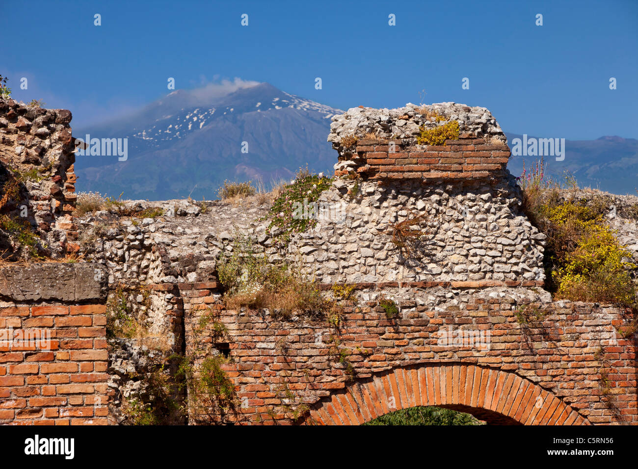 Ruins of the Greek Theatre (Teatro Greco) in Taormina with smoking Mt. Etna beyond, Sicily Italy Stock Photo