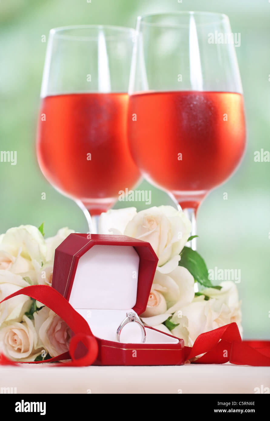 Marriage proposal. An engagement diamond ring in the box with roses and rose wine Stock Photo