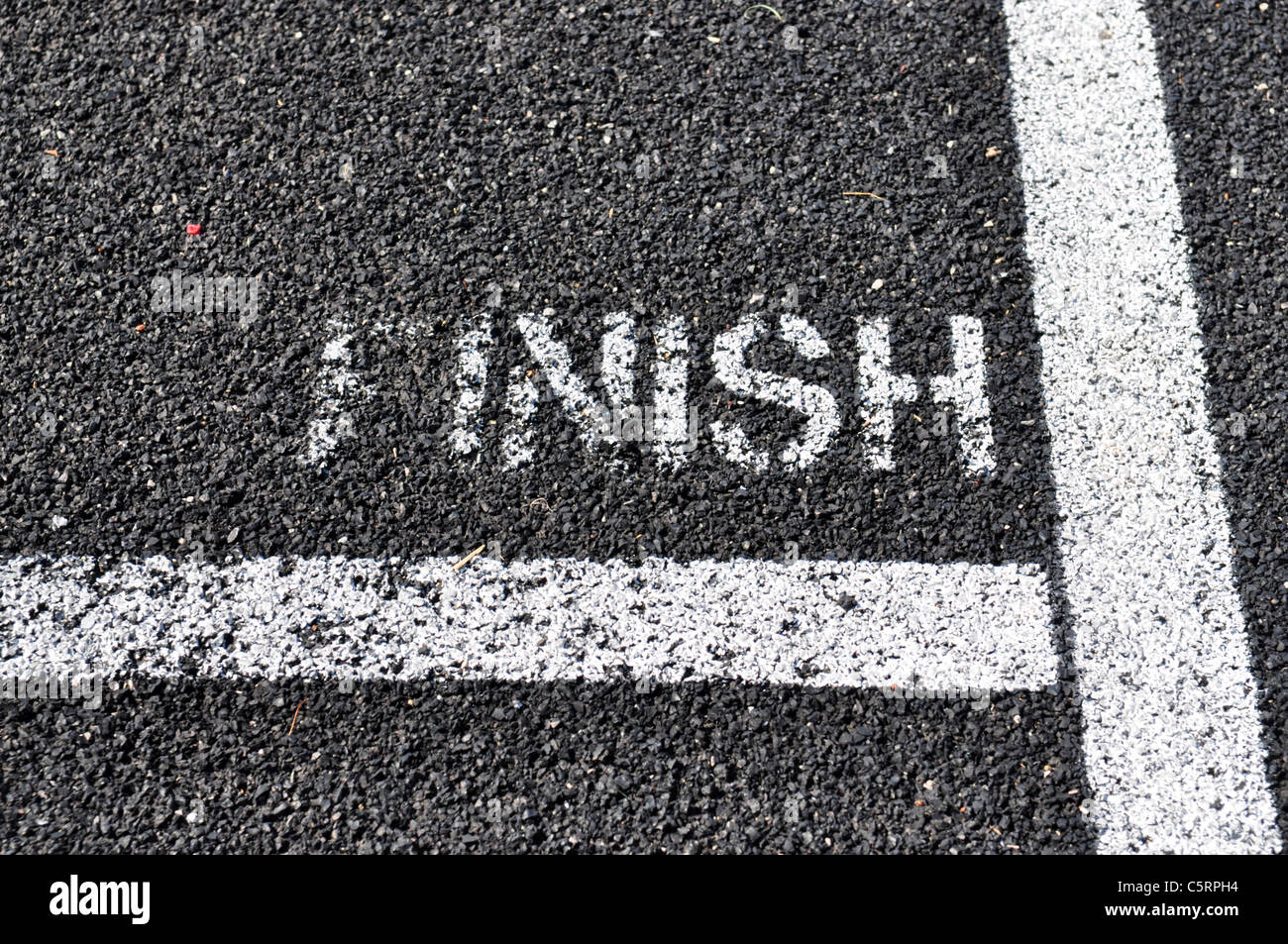 The worn finish line painted on a black top running tract. Stock Photo