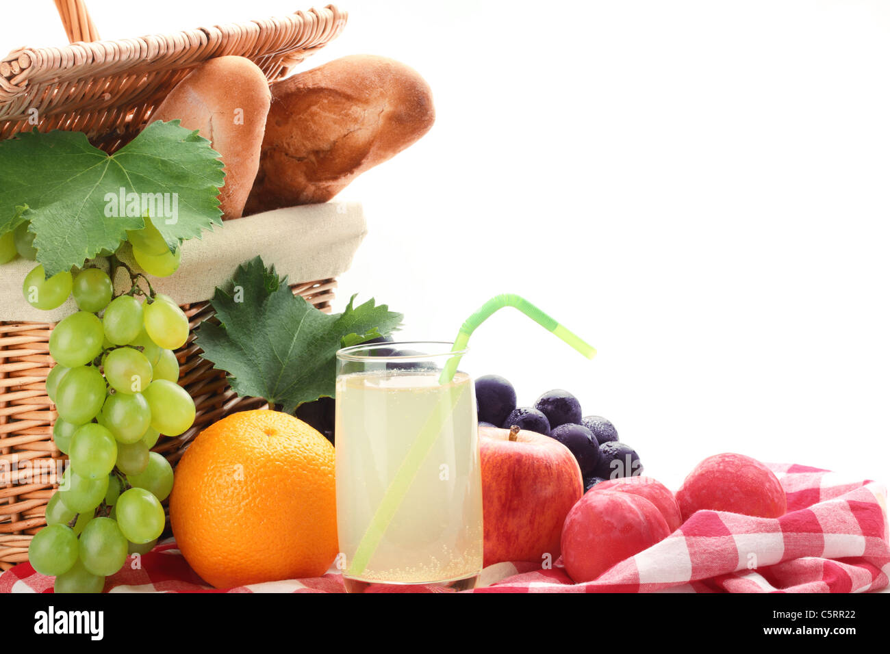 Picnic basket with fruits and a glass of lemon juice on white background. Stock Photo