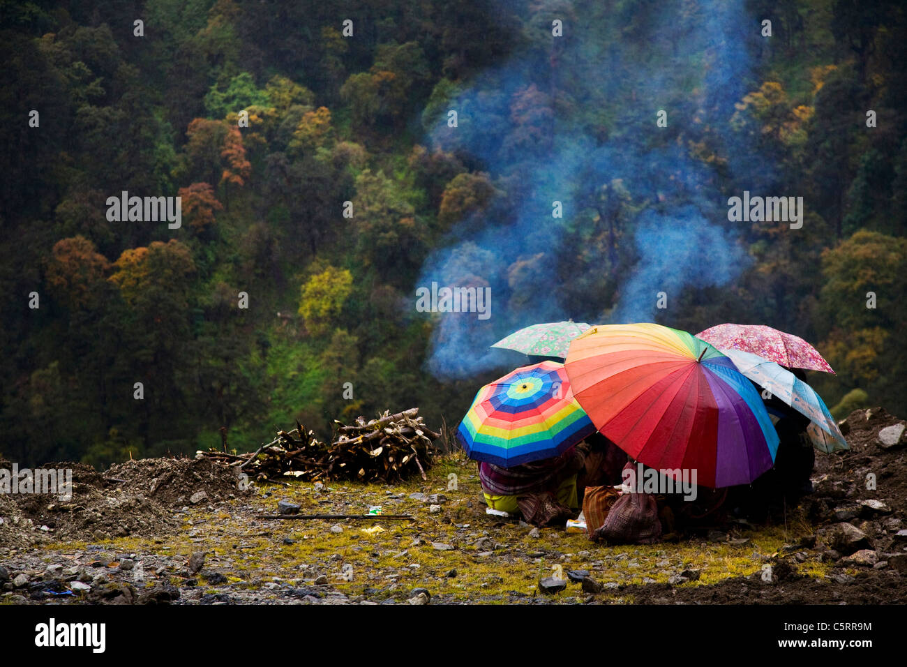 Road workers take shelter under their umbrellas as it drizzles. Tawang, Arunachal Pradesh. India Stock Photo