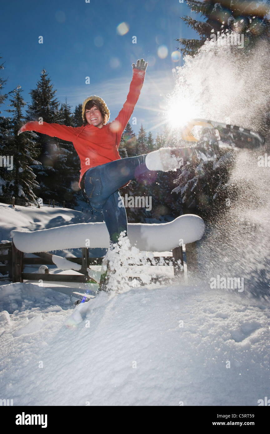 Austria, Salzburg Country, Flachau, Young woman wearing snow shoes jumping in snow Stock Photo