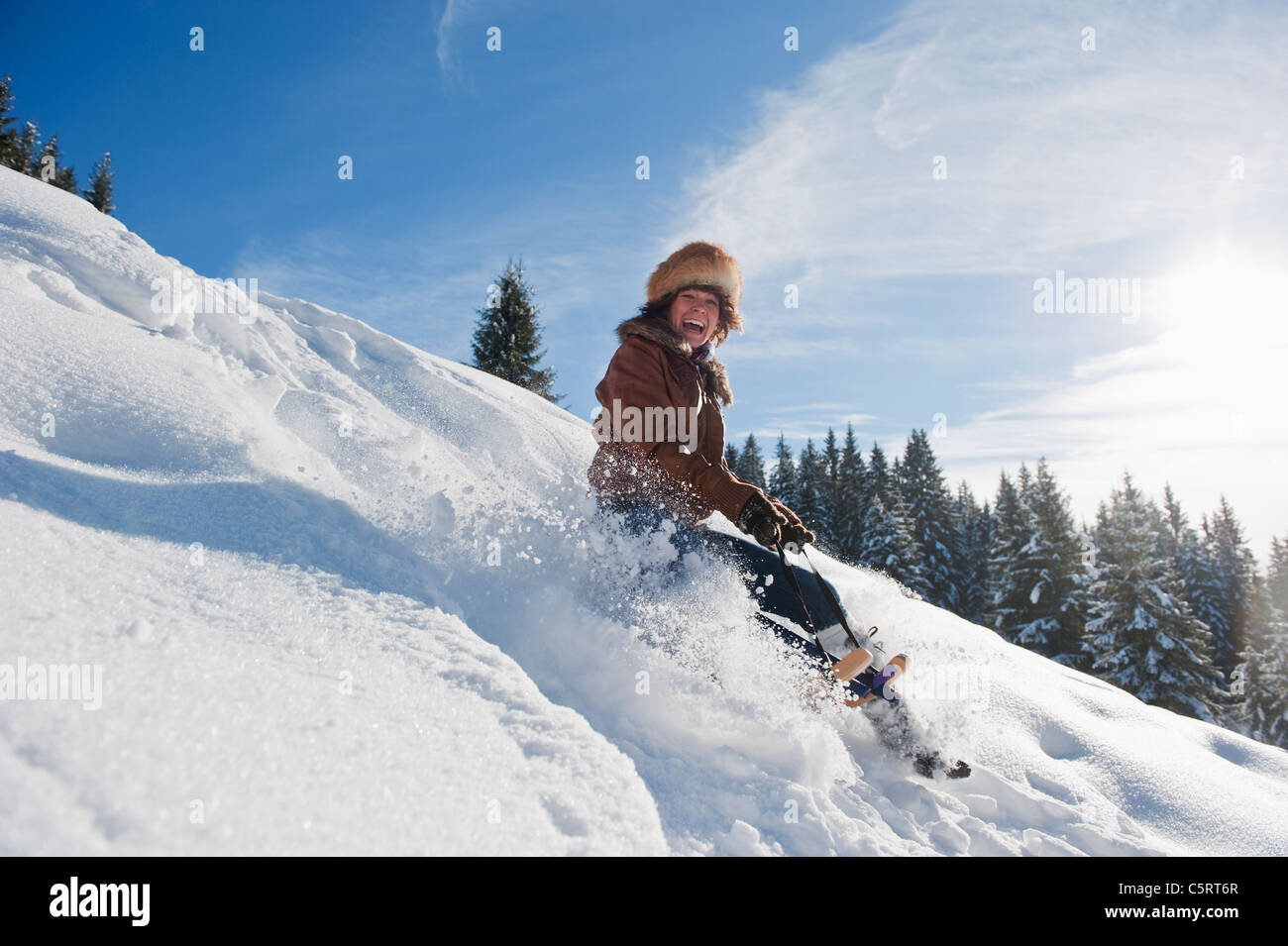 Austria, Salzburg Country, Flachau, Young woman tobogganing in snow