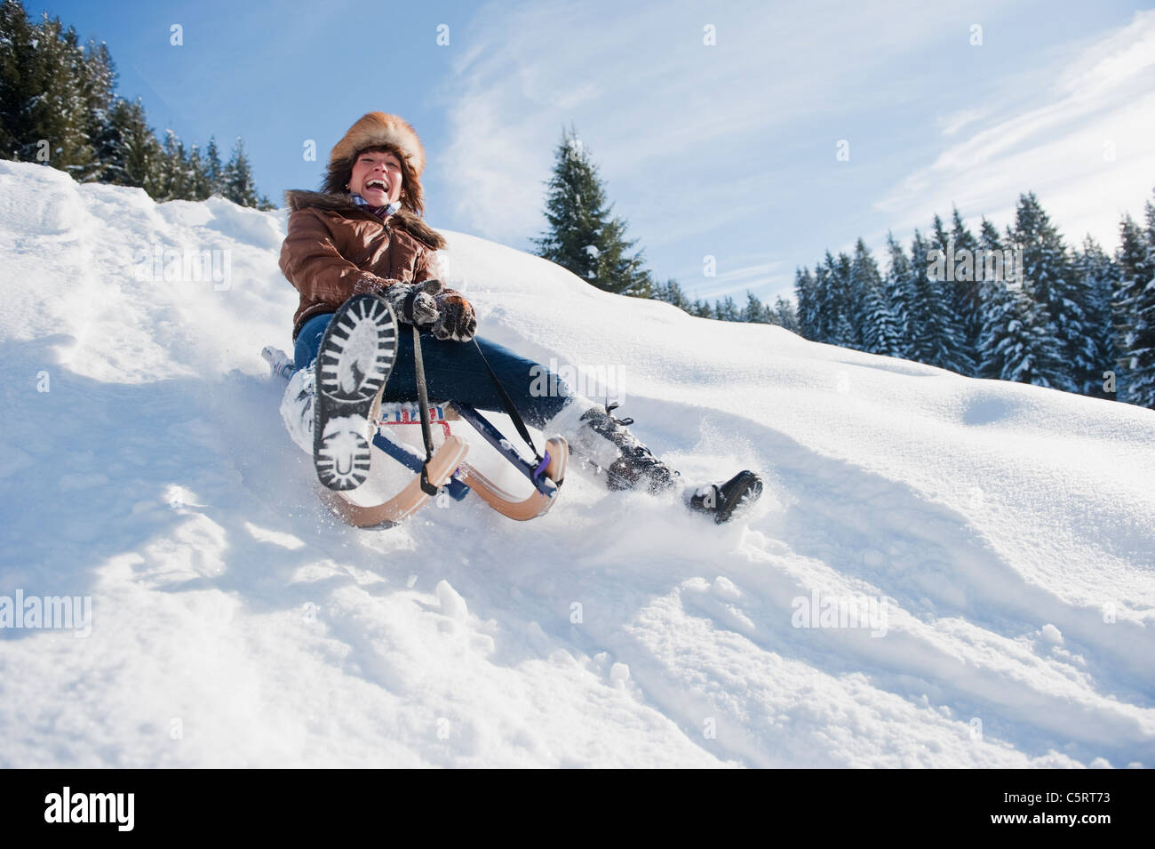 Austria, Salzburg Country, Flachau, Young woman tobogganing in snow