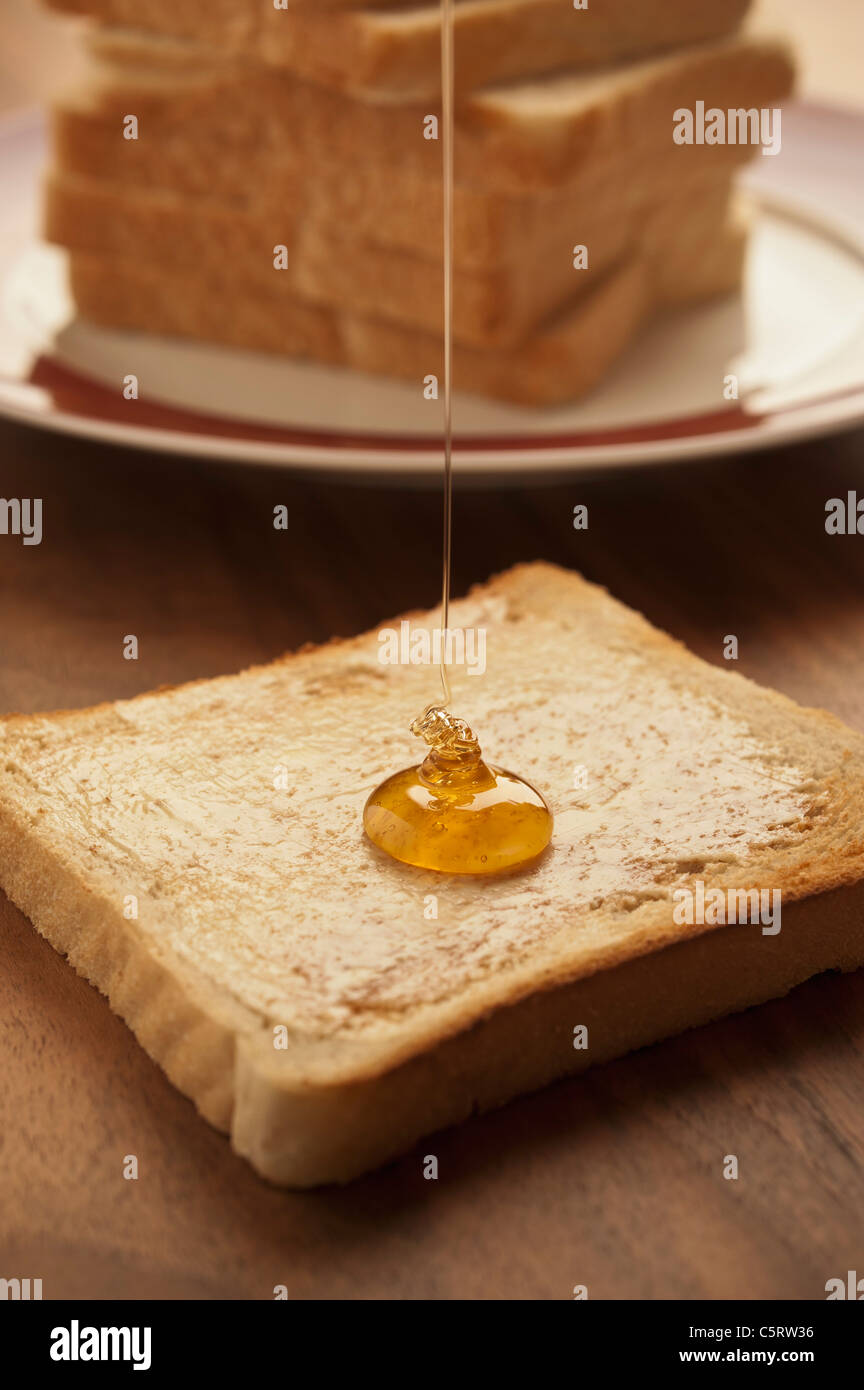 Germany, North Rhine-Westphalia, DÃ¼sseldorf, Close up of honey falling on toast Stock Photo