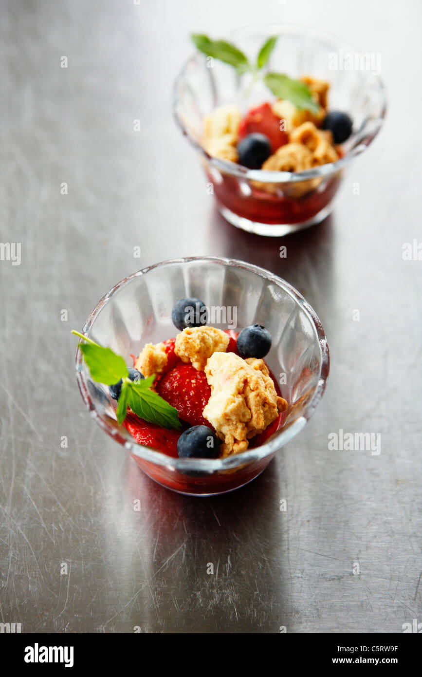 Close up of strawberry crumble with blueberries in glass bowl Stock Photo