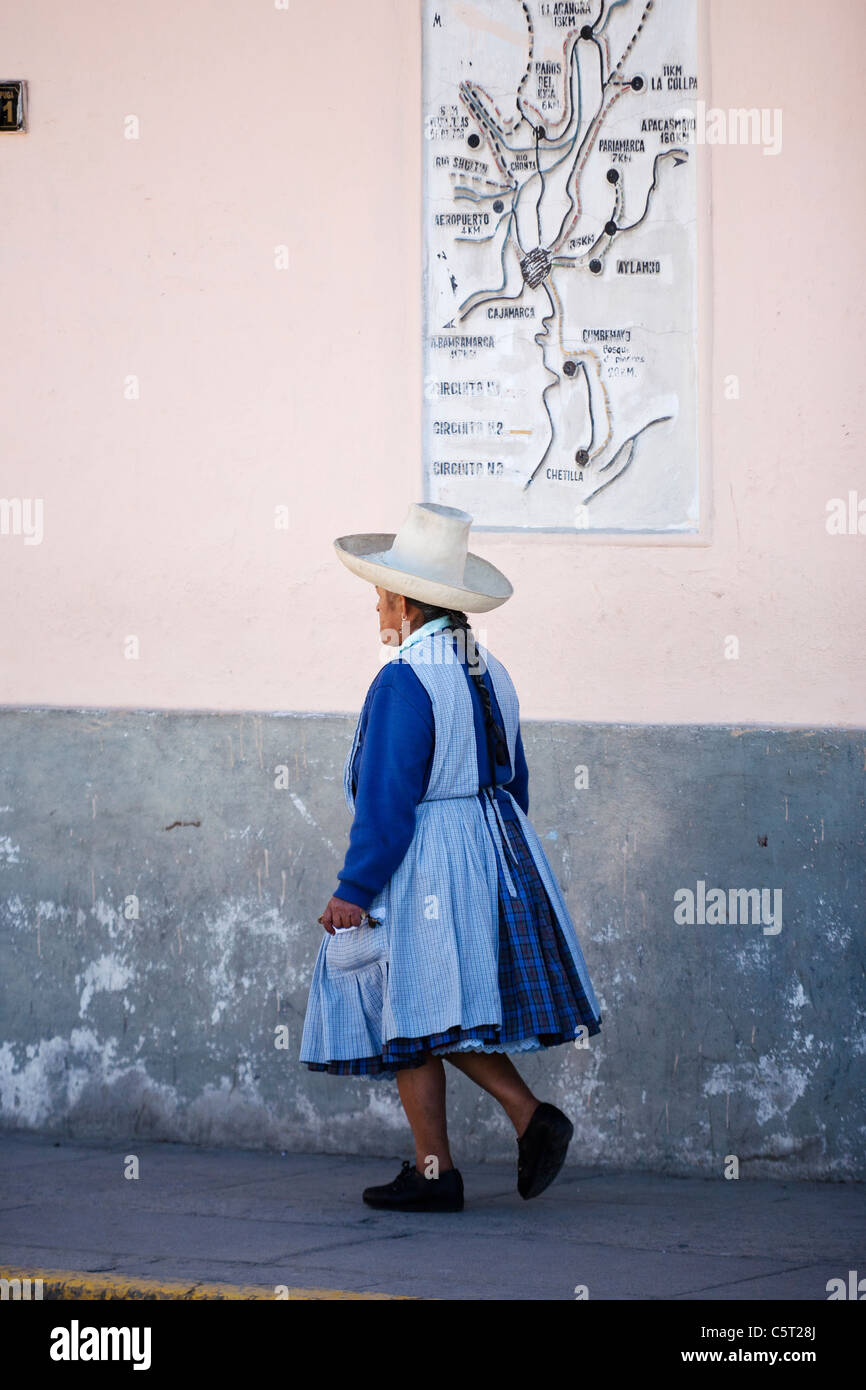 A woman walks past a wall and map in the downtown  of Cajamarca in the Northern highlands of Peru. Stock Photo