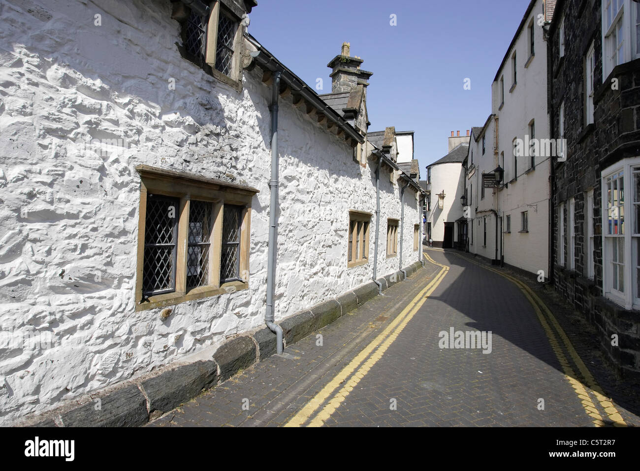 A row of historic stone built whitewashed Alms Houses on a narrow