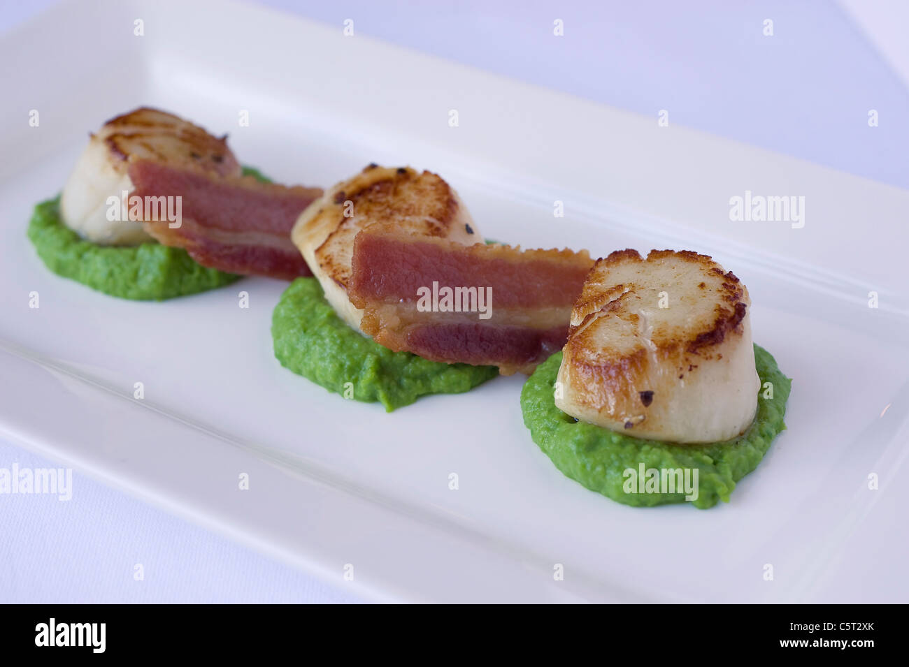 Pan fried scallops with crispy bacon and pea puree Stock Photo Alamy