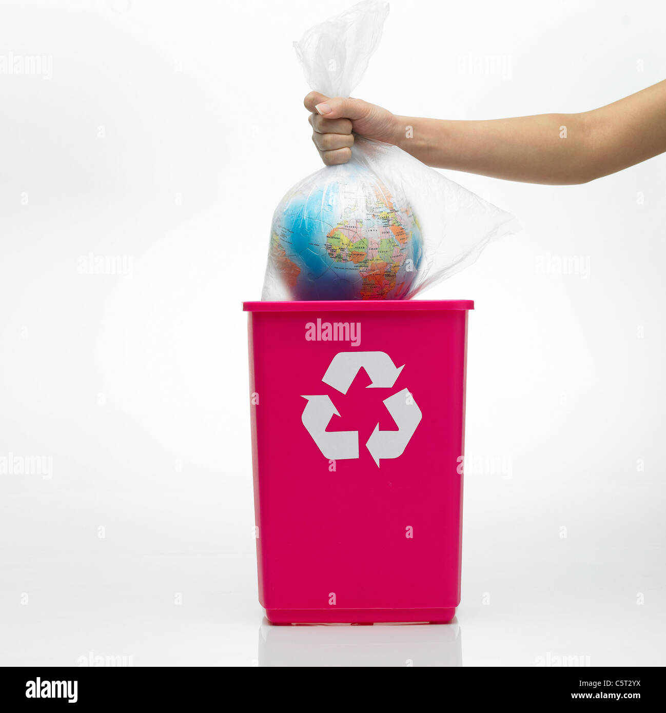 A hand putting a bag of globe inside a recycling bin Stock Photo