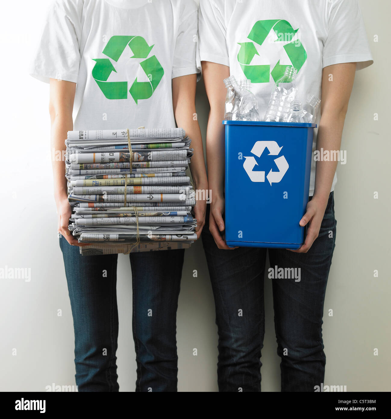 Two people holding stack of newspaper and recycling bin Stock Photo Alamy