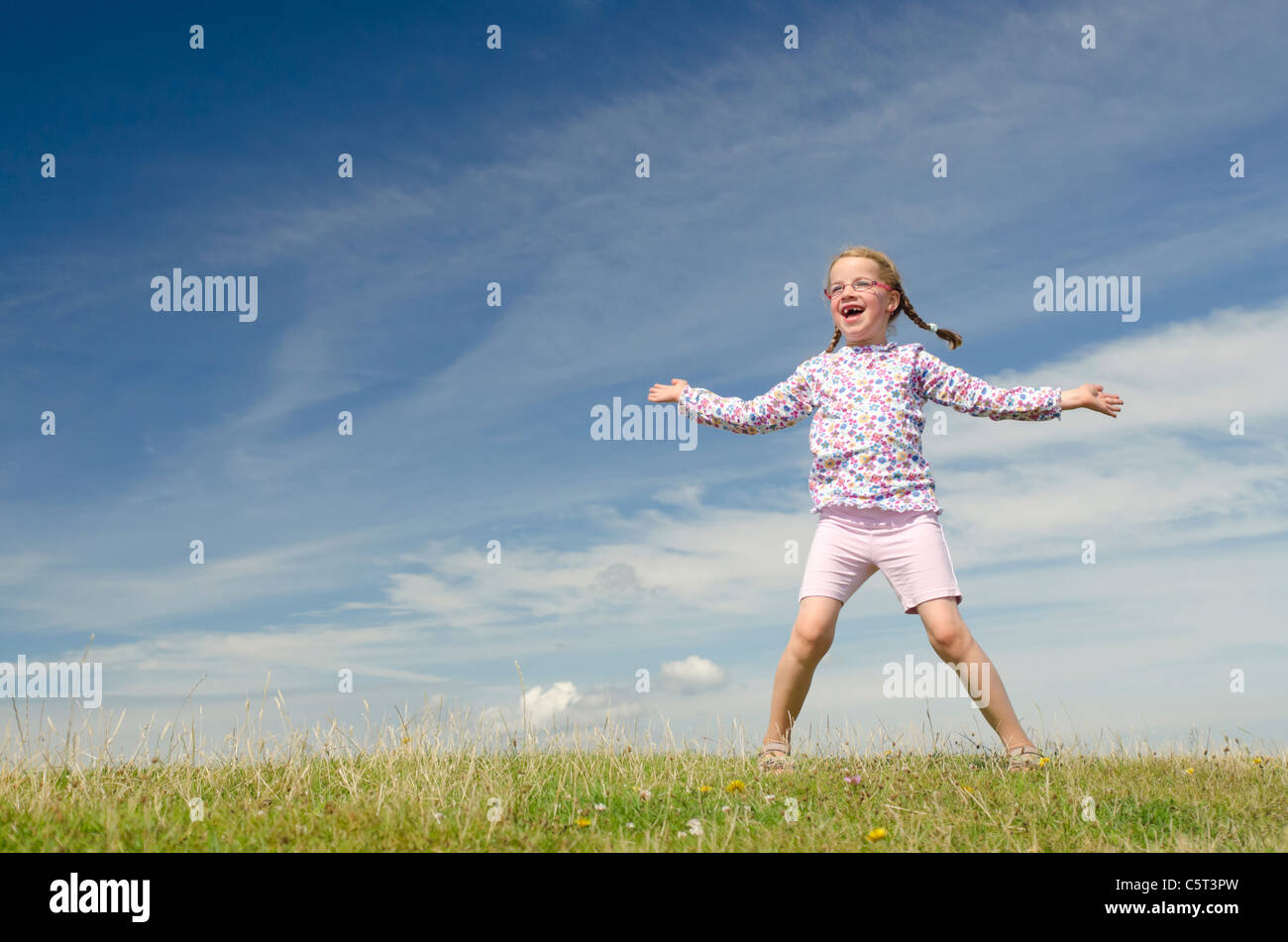 Happy little girl jumping in front of blue sky Stock Photo - Alamy