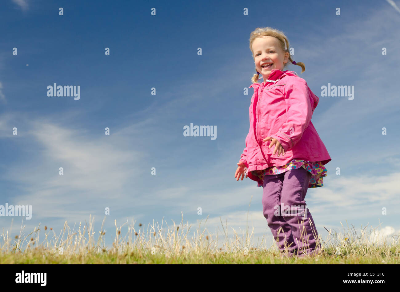 Happy little girl jumping in front of blue sky Stock Photo - Alamy