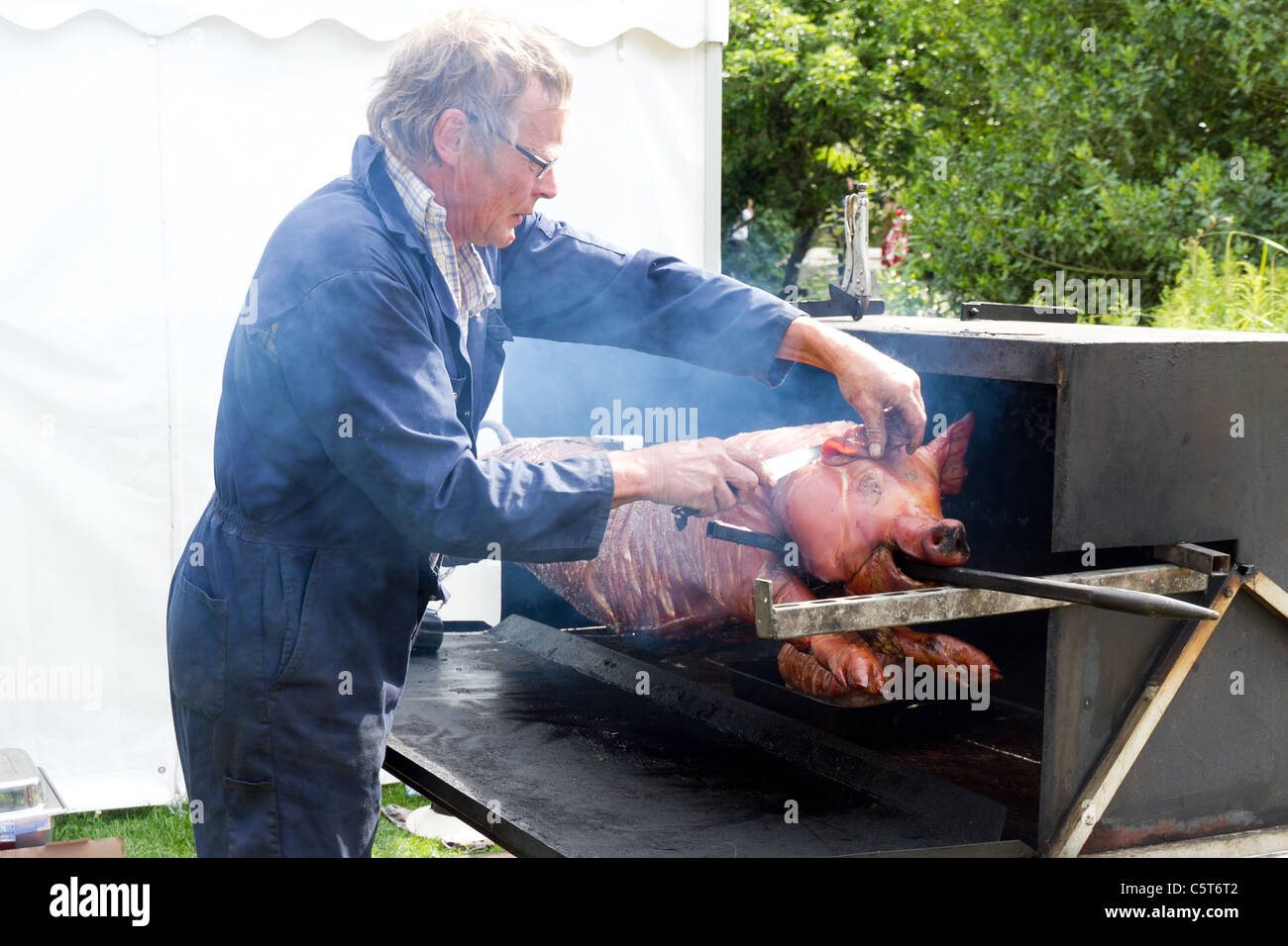 Whole roasted pig on spit being carved Stock Photo