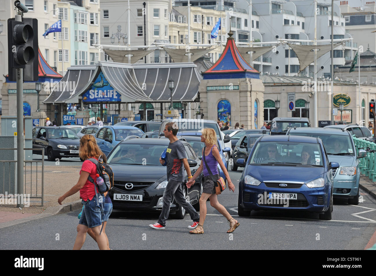 Pedestrians cross the road at a crossing on Brighton seafront in front of congested traffic as crowds flock to the beach Stock Photo