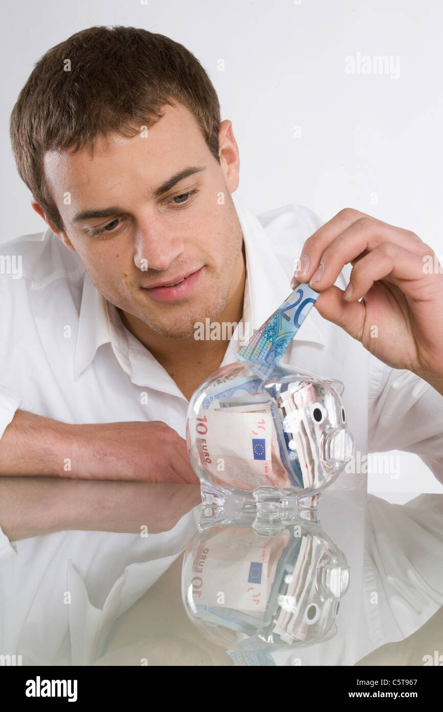 Man putting 20 Euro note in piggy bank Stock Photo
