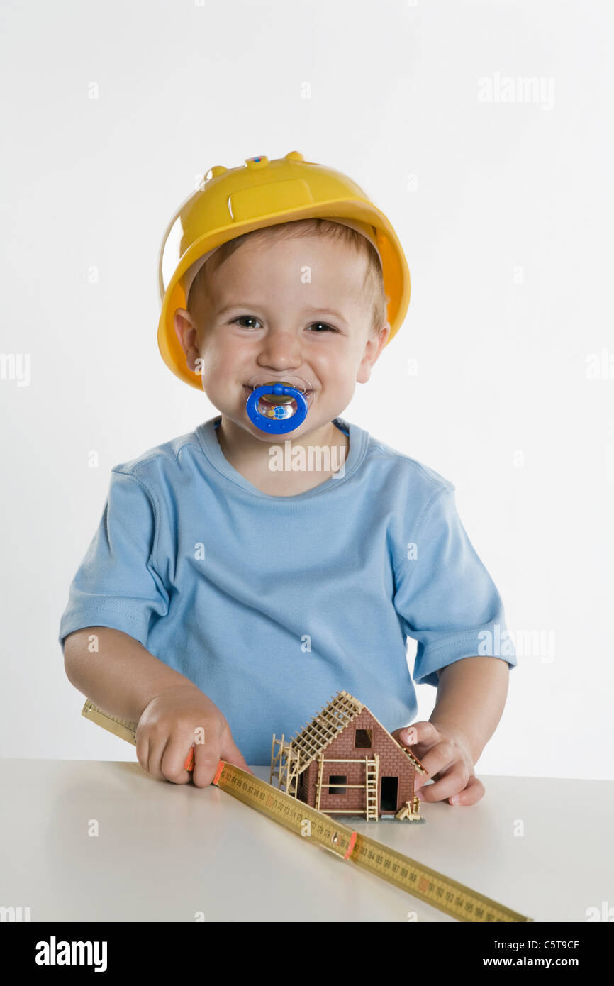 Boy (2-3) wearing hard hat, playing with folding rule Stock Photo