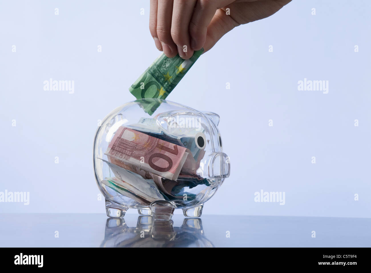 Man putting money into piggy bank Stock Photo - Alamy