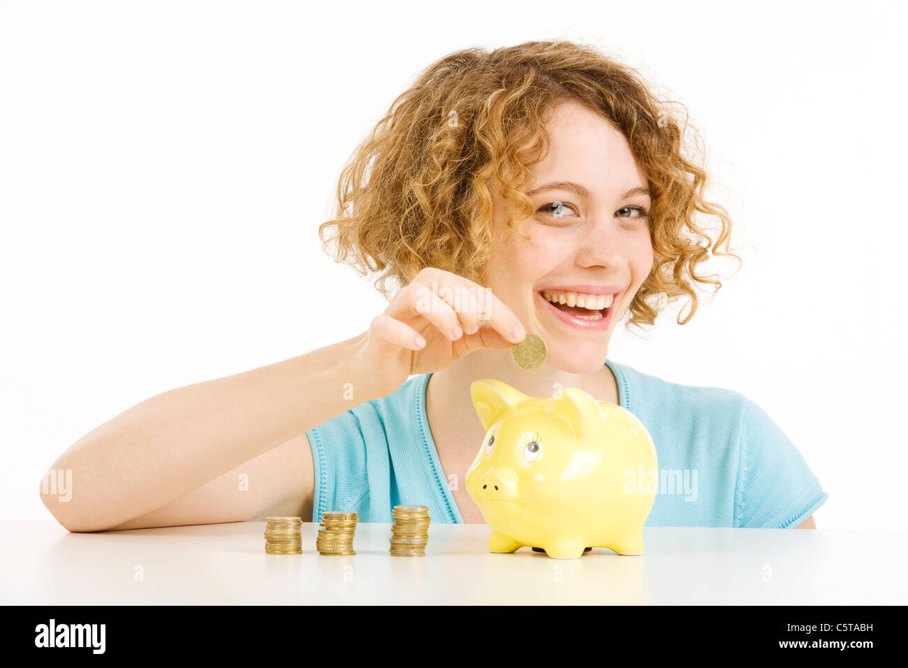 Young woman with Euro coins and piggy bank, smiling, portrait Stock Photo