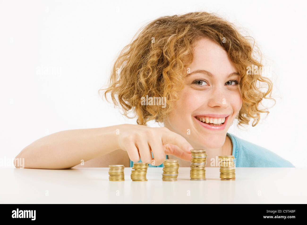 Young woman and stacked Euro coins, smiling, portrait Stock Photo