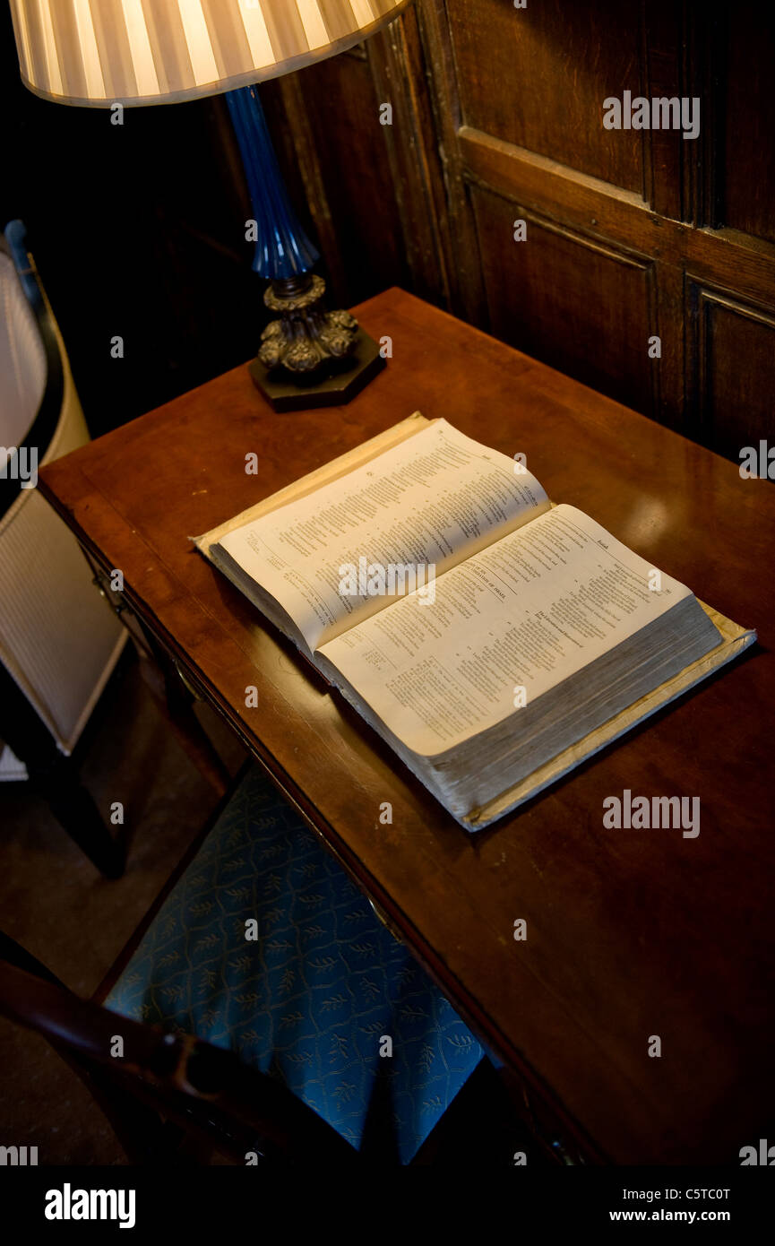 Old book open on antique oak desk with table lamp and oak panelling Stock Photo