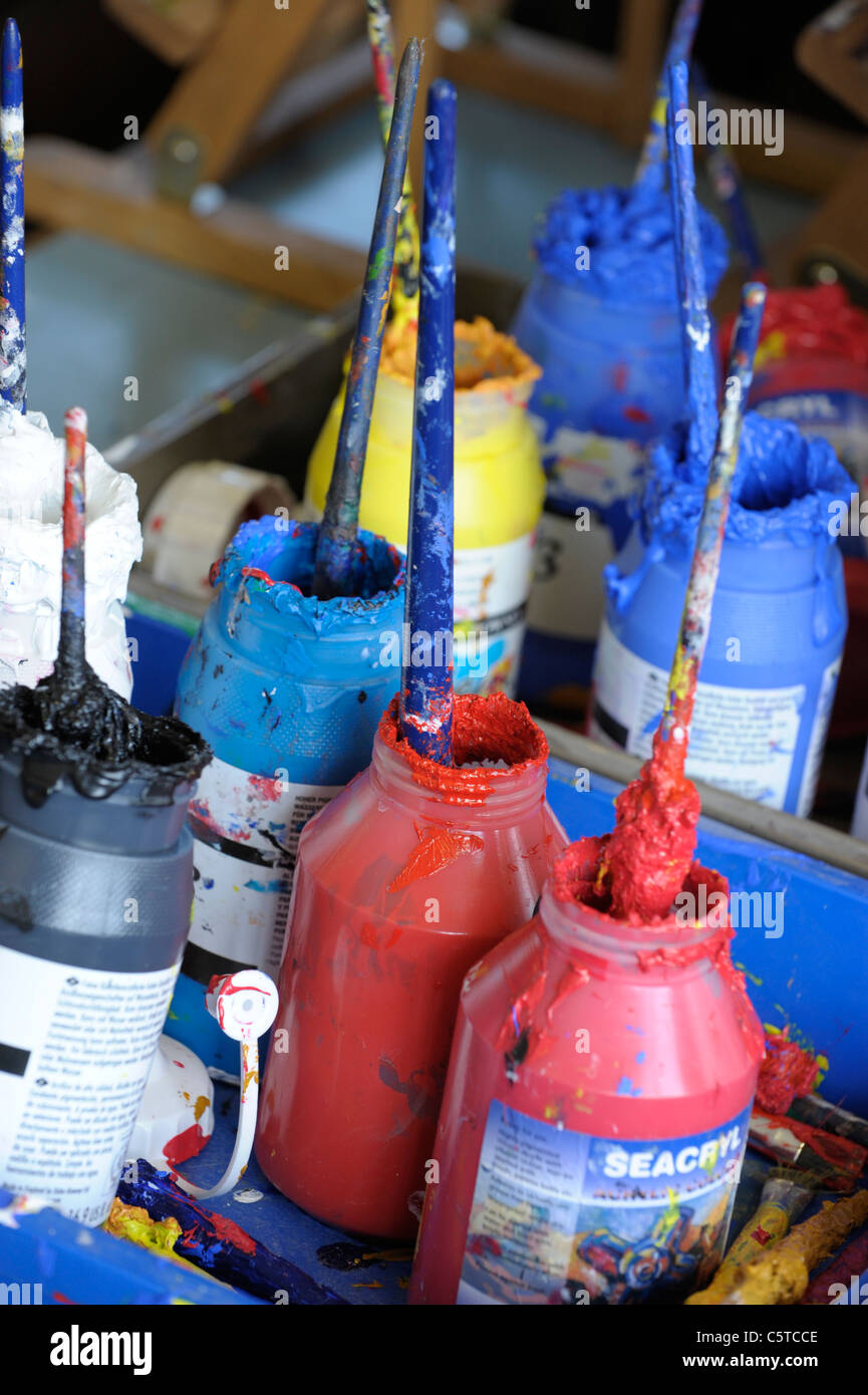 Messy acrylic paint pots in an art room setting Stock Photo Alamy