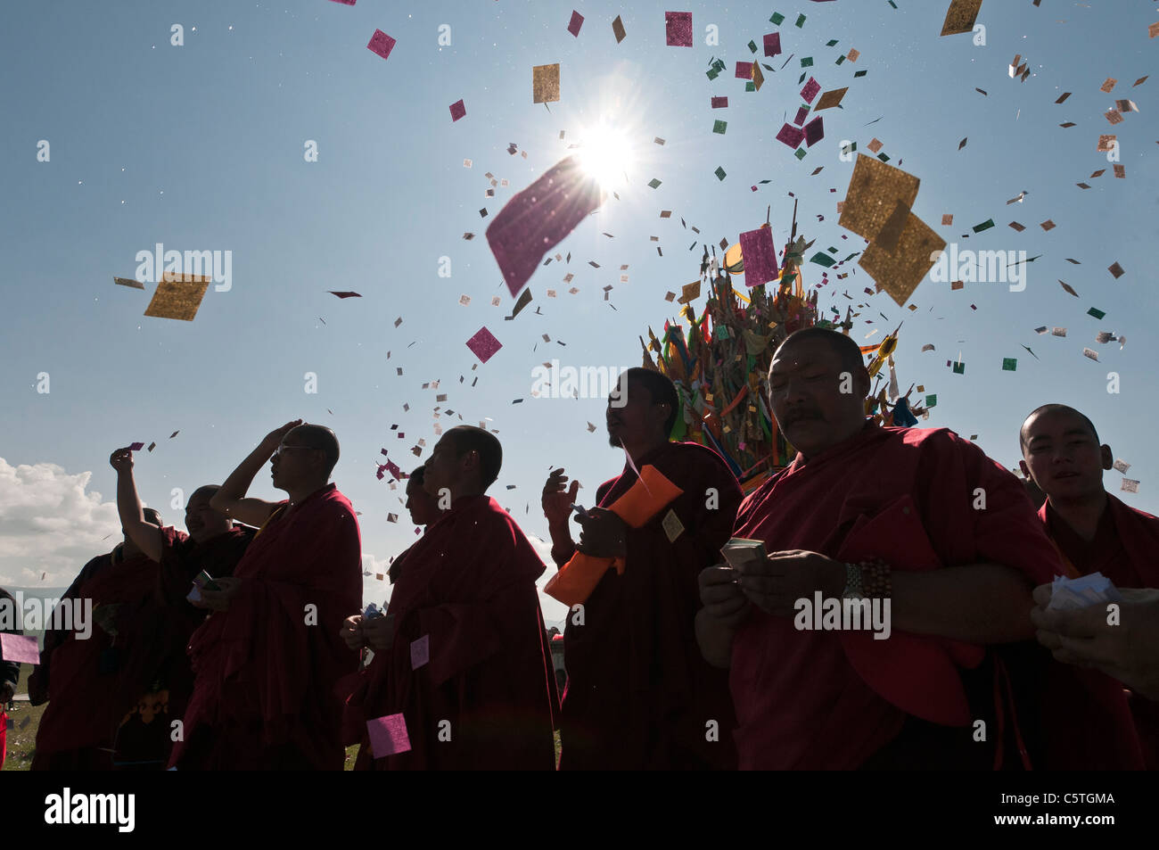 Tibetan Buddhist monks toss paper prayers during harvest ceremony on