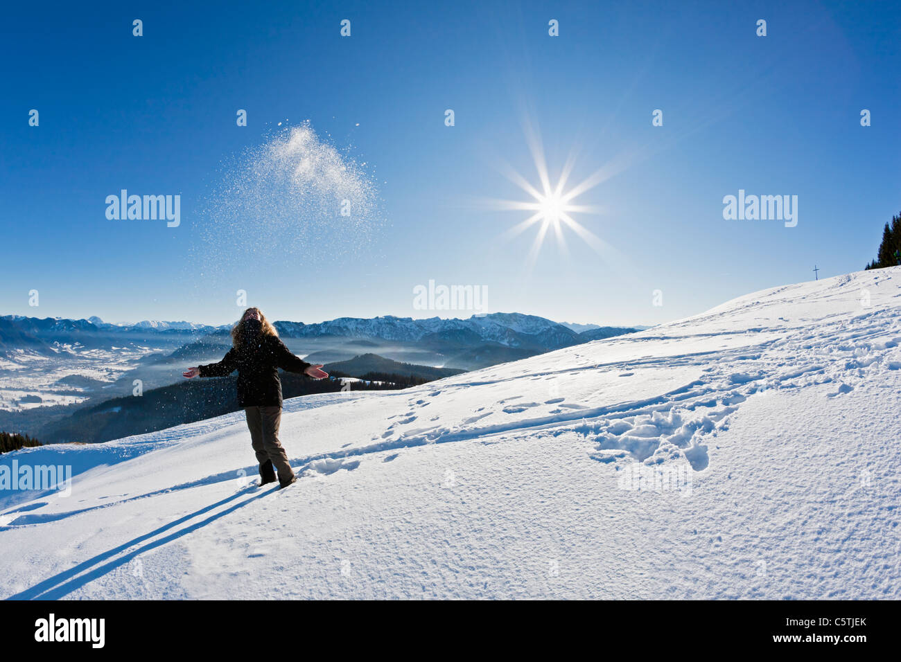 Germany, Bavaria, Blomberg, Woman hiker at Zwiesel mountain throwing snow Stock Photo