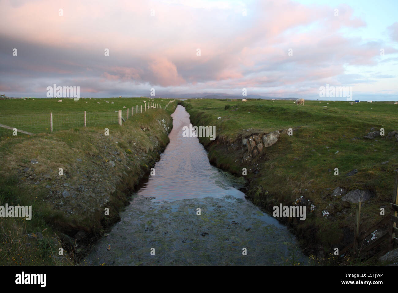 Drainage dyke seen at Eilean Siar, South Benbecula, Outer Hebrides against a low sun Stock Photo