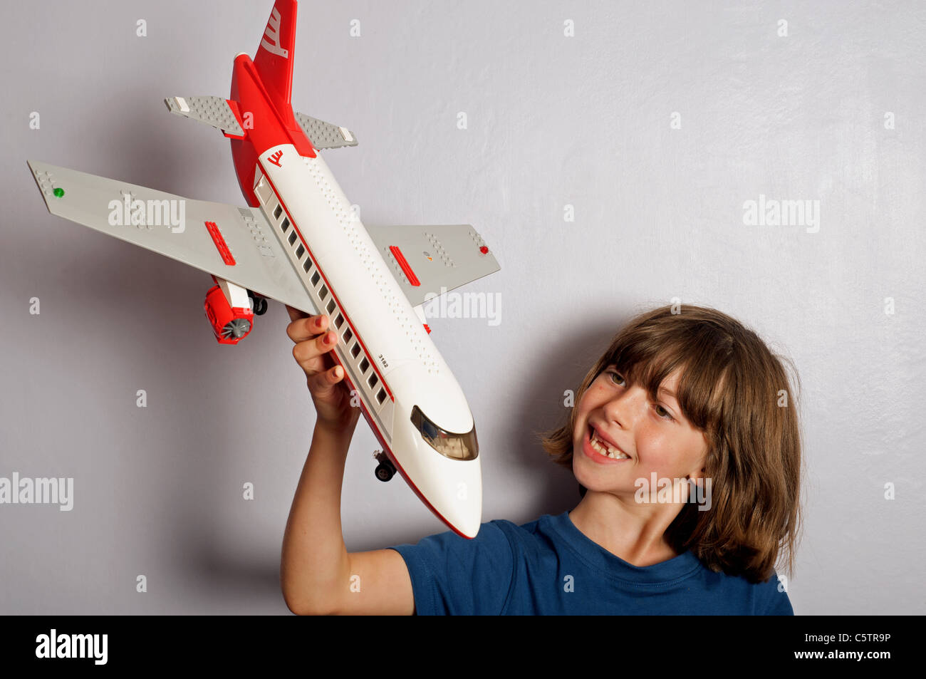 Young girl (tomboy) playing with a Lego model jet airliner Stock Photo