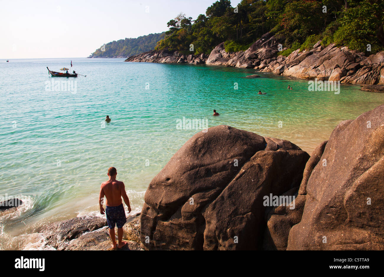 Longtail Boats anchored along Freedom Beach and people swimming in the Andaman Sea . Stock Photo