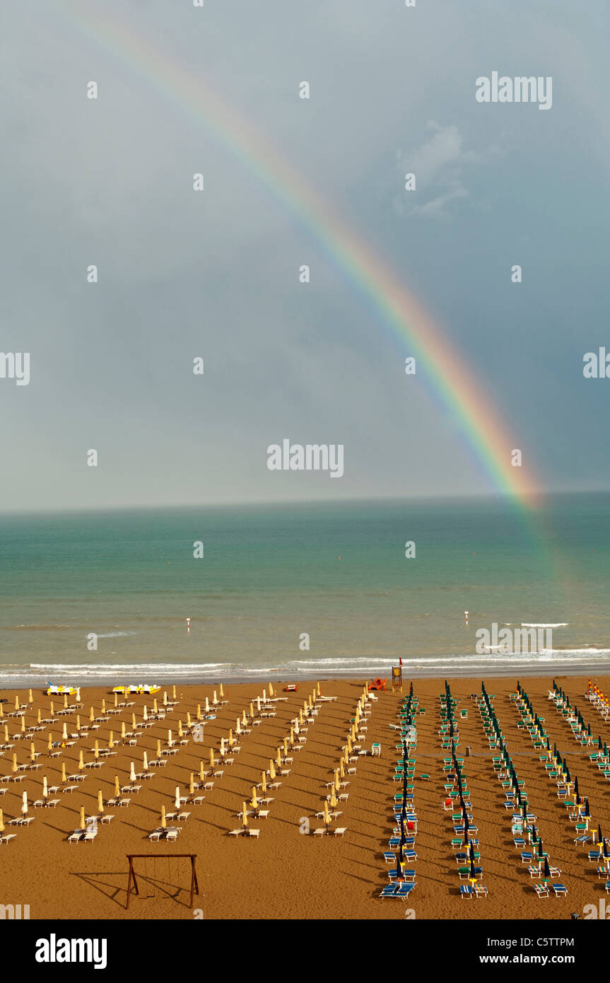 Italy, Lignano Beach with sunloungers, rainbow in background Stock Photo