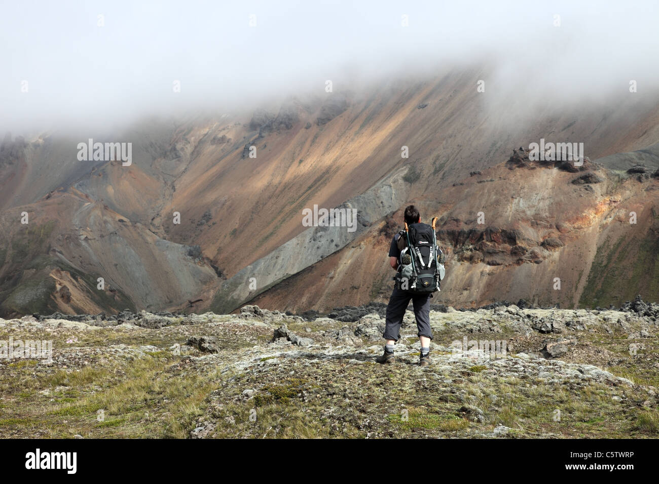 Hiker Looking Towards the Cloud Covered Rhyolite Mountains Near Landmannalaugar Iceland Stock Photo