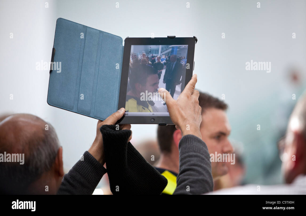 An iPad 2 is held aloft to take a photograph with it's built in camera. Stock Photo