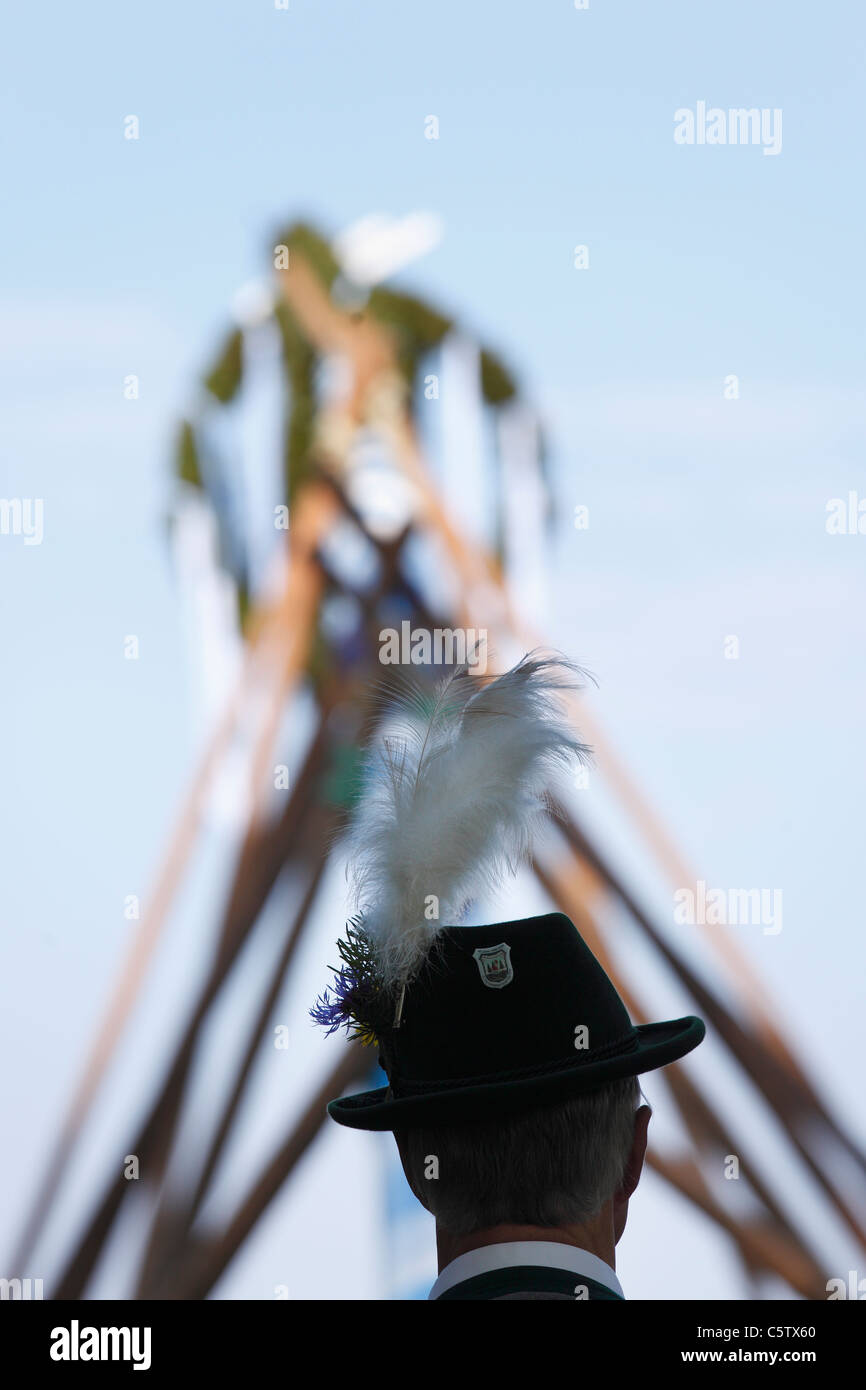 Germany, Bavaria, Upper Bavaria, Holzhausen, Man with hat in front of maypole Stock Photo